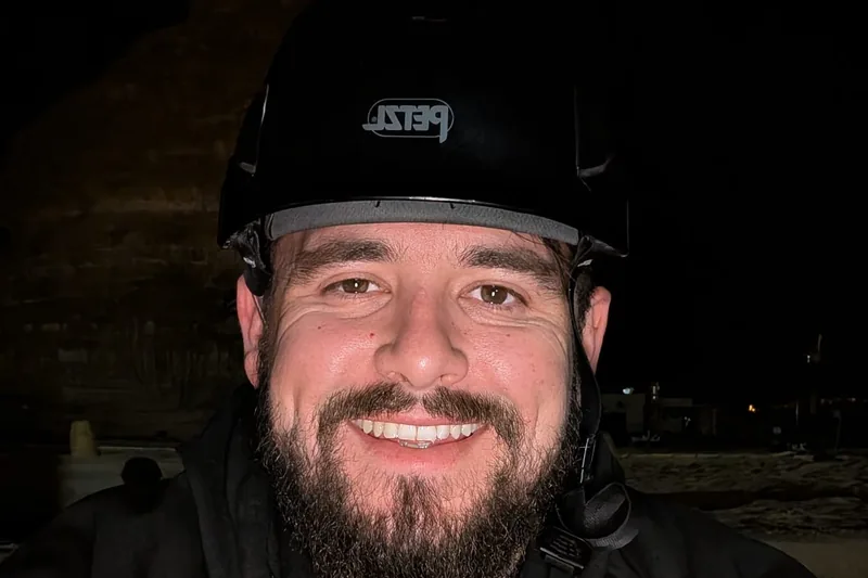 Kris Dailly, founder of OTAS, on site at night in a safety helmet with a radio headset.