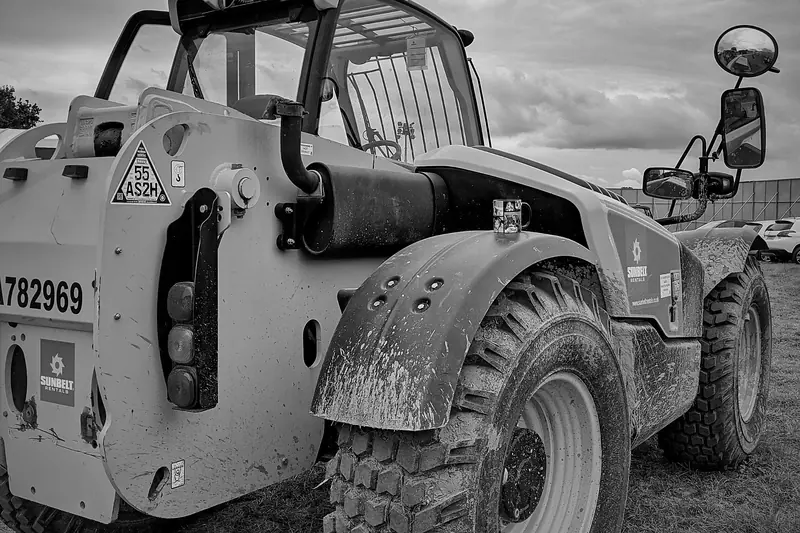 Black and white photo of a telehandler parked on a festival site.
